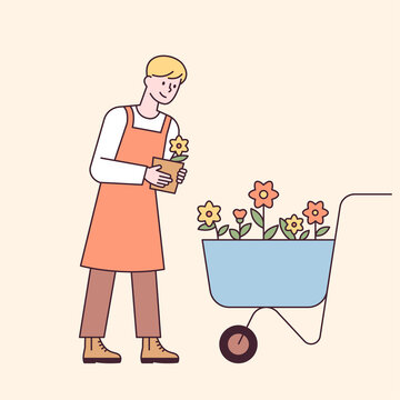 A man in an apron carries flowers in a cart. flat design style minimal vector illustration.