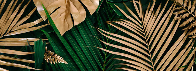 Creative nature background. Gold and green tropical Monstera and palm leaves. Minimal summer abstract jungle or forest pattern.