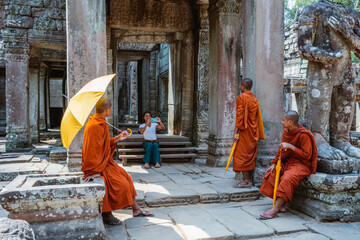 Woman taking a photo of three monks at Angkor Wat