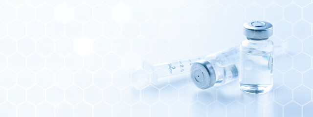 Medical syringe with a needle and a bollte with vaccine.