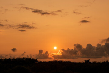 Beautiful dawn with the sun rising in orange colors and beautiful clouds composing the scene. Iriomote Island.