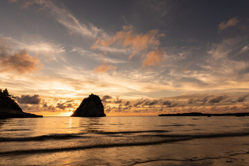 Relaxing sunset with beautiful colors and the sun descending behind the rock in the sea from Tsukigahama beach. Iriomote Island.