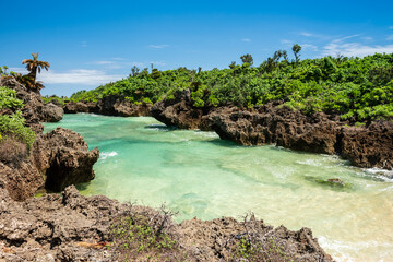 Obraz premium Beautiful beach for relax with emerald green sea, blue sky, green vegetation and rock formation typical of Okinawa in Unarizaki park. Iriomote Island.