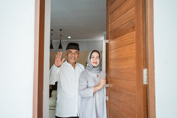 portrait of muslim asian senior couple standing at front door waiting for family to come