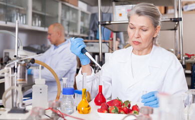 Professional female geneticist working in laboratory, conducting experiments with genetically modified fruits and vegetables