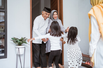 Happy asian muslim aged couple meeting kids and grand children at doorstep during eid mubarak...