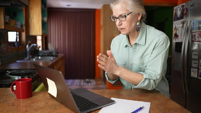 Mature successful woman pray for success victory triumph looking at laptop video chat. Concept of female success businesswoman teacher tutor.