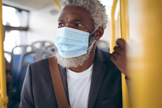 African american senior man wearing face mask standing on bus