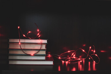 Stack of books on a shelf illuminated with red lights; String of lights around a collection of...