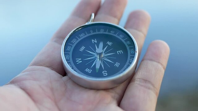 Close up of hand holding a compass over nature background for journey. Lifestyle and Vacation concepts.