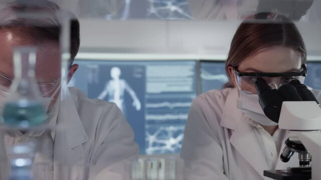 Diverse scientists studying human skeleton and DNA. Using computers and microscopes, discussing