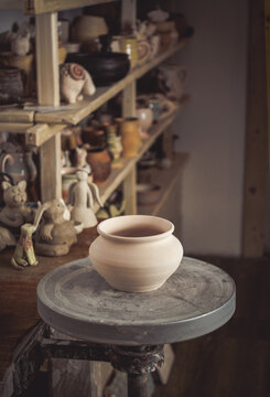 Clay pot in the foreground and shelves with pottery - on the second