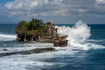 Tanah Lot temple Bali, Indonesia with ceremony decoration in high tide time. big wave smash the temple cliff when the tide is high.