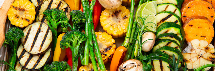 Grilled assorted vegetables in beige tray on light grey background.