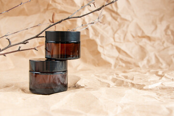 Cometic bottles made of amber glass on crumpled craft paper. Skin care products packaging design. Spa concept.