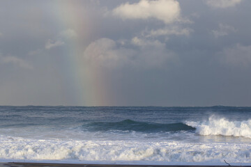 A stunning Vivid Rainbow formed over the Pacific Ocean close to where a large surfing competition is held in Chiba, Japan. There are large waves breaking onto the beach. It's close to Tokyo