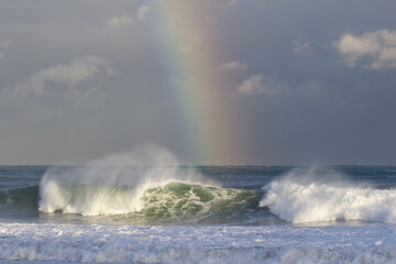 Fototapeta na wymiar A stunning Vivid Rainbow formed over the Pacific Ocean close to where a large surfing competition is held in Chiba, Japan. There are large waves breaking onto the beach. It's close to Tokyo