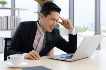 Confused ethnic male entrepreneur working on laptop in office