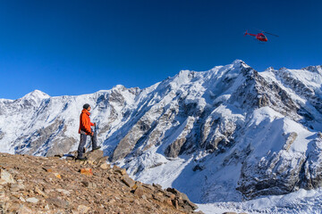 A beautiful landscape with mountains, a huge blue glacier and a middle-aged mountain climber on the...