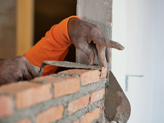 Brick worker stacking red bricks layer 