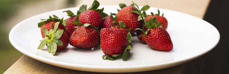 Juicy ripe strawberries on a white plate.