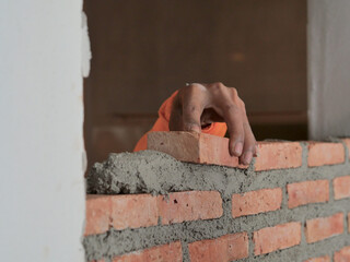 Worker stacking red brick on the concrete layer
