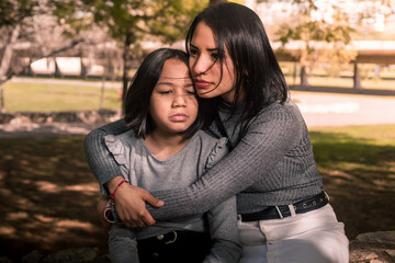 Young mother comforting her daughter outside at the park.