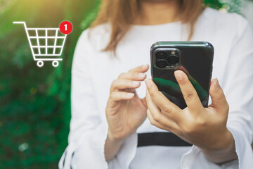 Woman using mobile smart phone, online payment, banking and online shopping with shopping cart icon on green background.