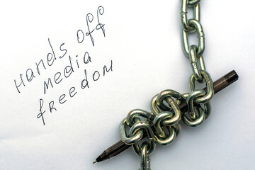 a fountain pen wrapped in an iron chain on sheets of white paper with the inscription hands off media freedom the concept of freedom of speech