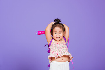 Thai child funny hold toy water pistol and smile, Happy Asian little girl holding plastic water gun, studio shot isolated on purple background, Thailand Songkran festival day national culture concept