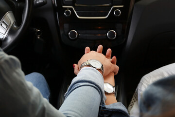 Young couple holding hands in car
