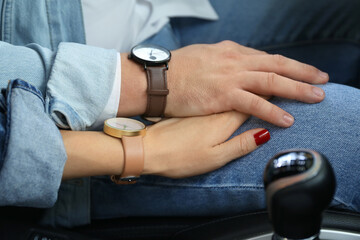 Young couple holding hands in car