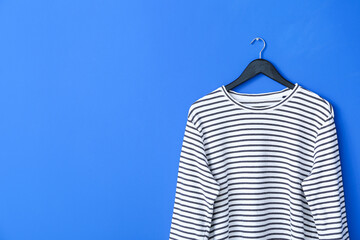 Hanger with sweatshirt on color background