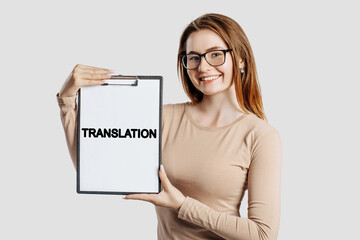 Naklejka premium TRANSLATION. Beautiful young business woman wearing glasses holds a clipboard with mock up space isolated on gray background