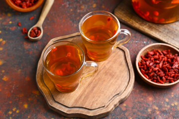 Glass cups of hot tea with goji berries on grunge background