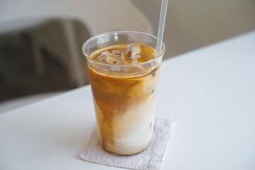 Ice coffee in a tall glass placed on a white table