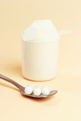 Protein scoop and capsules on brown background close-up