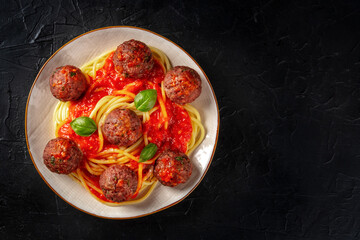 Meatballs with spaghetti, overhead shot on black with copyspace