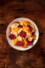 Healthy fruit and vegetable chips, top shot on a dark rustic wooden background with a place for text