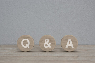 Q and A letter on wood circle shape on wooden table over white wall background, Frequently asked...