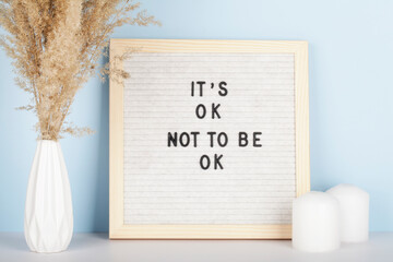 Dried pampas grass in vases, candles and felt letter board with phrase it is ok not to be ok on...