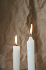 Fototapeta na wymiar Beautiful white burning candles on table against paper craft background