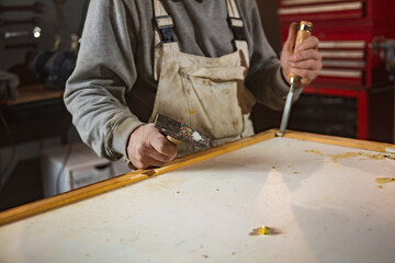 Male carpenter working on old wood in a retro vintage workshop.