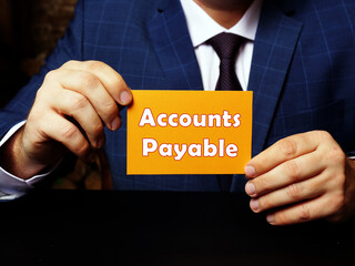 Man's hand showing orange business card with phrase Accounts Payable - closeup shot on grey...
