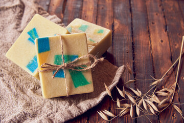 Fototapeta na wymiar A fragrant organic handmade soap with a geometric pattern , a linen napkin and a few dry spikelets .