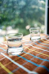 Two glasses of water on the table by the window