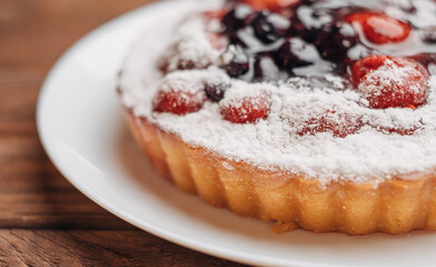 Simple homemade pie with strawberries and cherries on a wooden table.