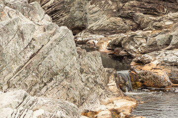 some water flowing over rocks i an almost dry river bed forming a very small waterfall close to...