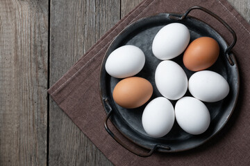 Fresh eggs in a metal tray on an old wooden table. Copy space.