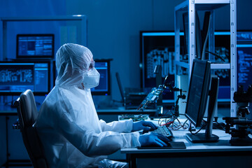 Microelectronics engineer works in a modern scientific laboratory on computing systems and microprocessors. Electronic factory worker is testing the motherboard and coding the firmware.